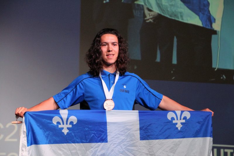 Mathieu Bernier tient fièrement le drapeau du Québec, médaille au cou. | Photo: Gracieuseté