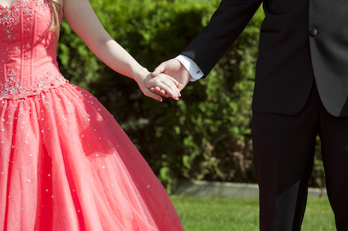 Close cropped outdoor photo of couple dressed in formalwear holding hands